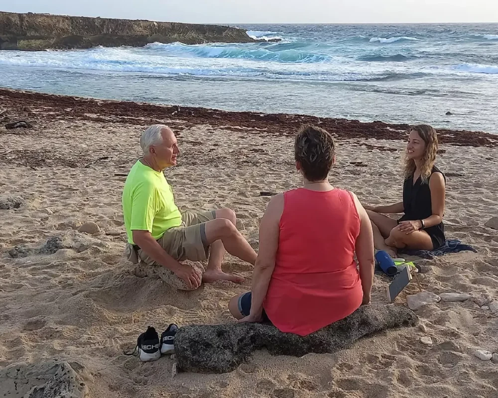 Guests seated on white sand beach for guided meditation in Aruba